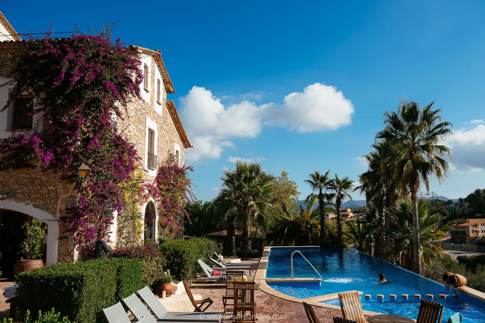 Stone façade of Almiral de la Font with bougainvillea and pool