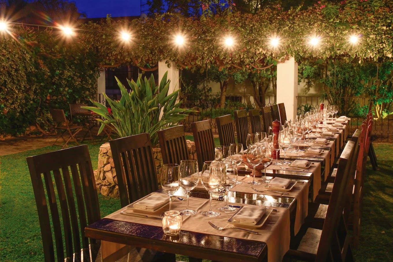 Mesa de cena en el jardín con luces