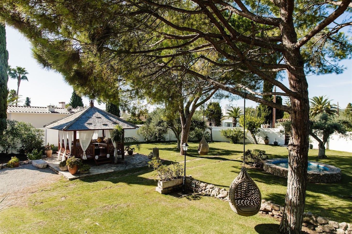 Jardín con pinos y sillones colgantes