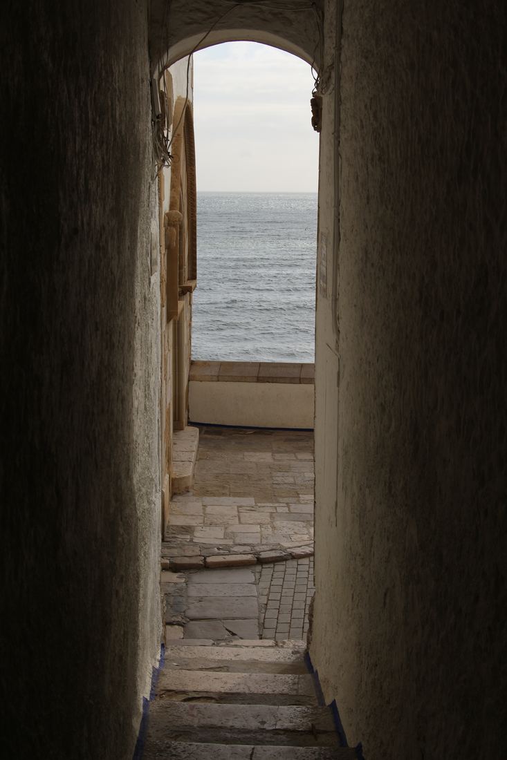 Callejón blanco del casco antiguo de Sitges que desemboca en el mar