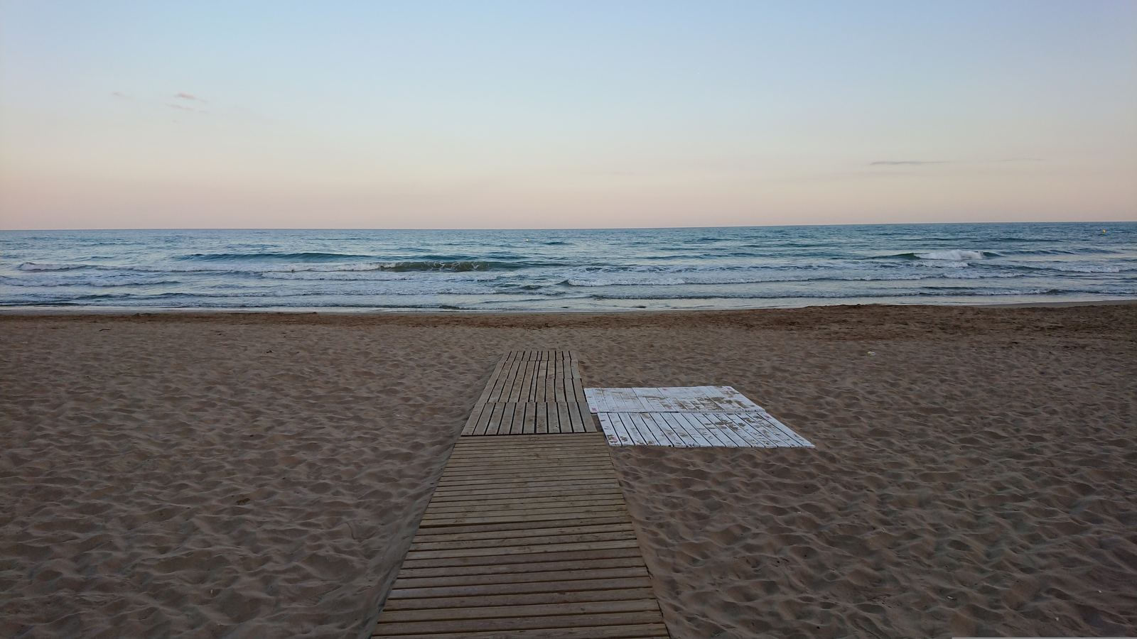 Playa de Sitges al amanecer con pasarela de madera